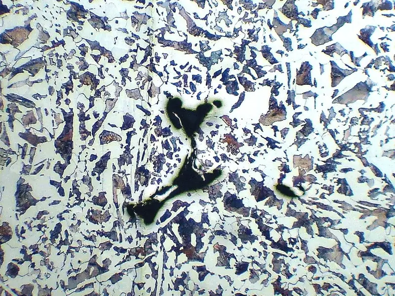 Micrografia mostrando inclusão escura em matriz metálica